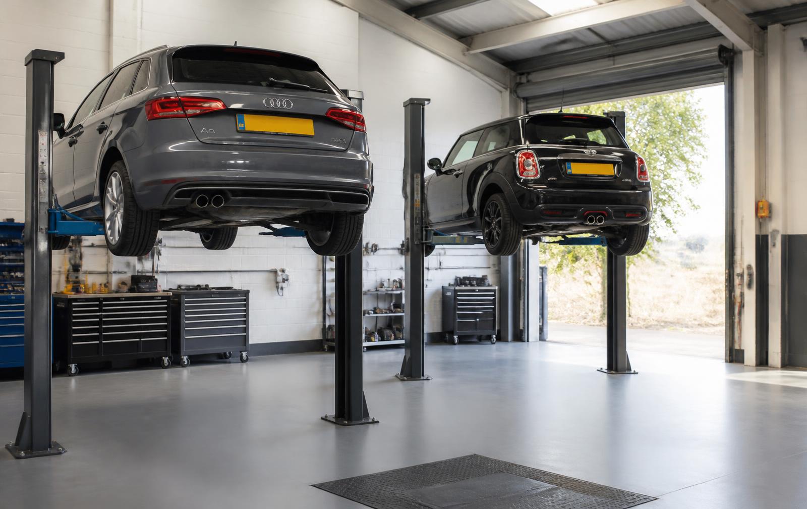 Two cars raised on ramps inside the workshop